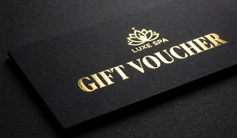 Thiết kế voucher thẩm mỹ viện màu đen ép kim vàng sang trọng.