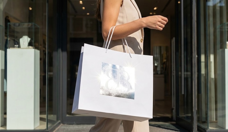 Khách hàng xách chiếc túi giấy ép kim sang trọng mua sắm tại Boutique.