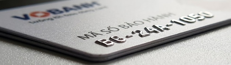 Cận cảnh độ dày chuẩn thẻ ATM và kỹ thuật dập nổi chữ trên thẻ bảo hành nhựa cứng.